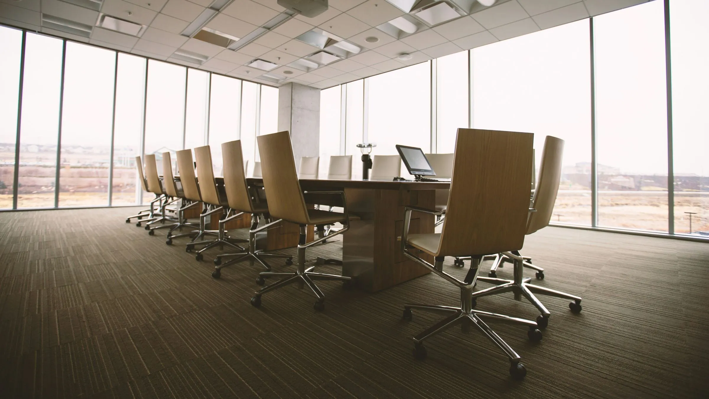 An empty boardroom with long windows and a conference table