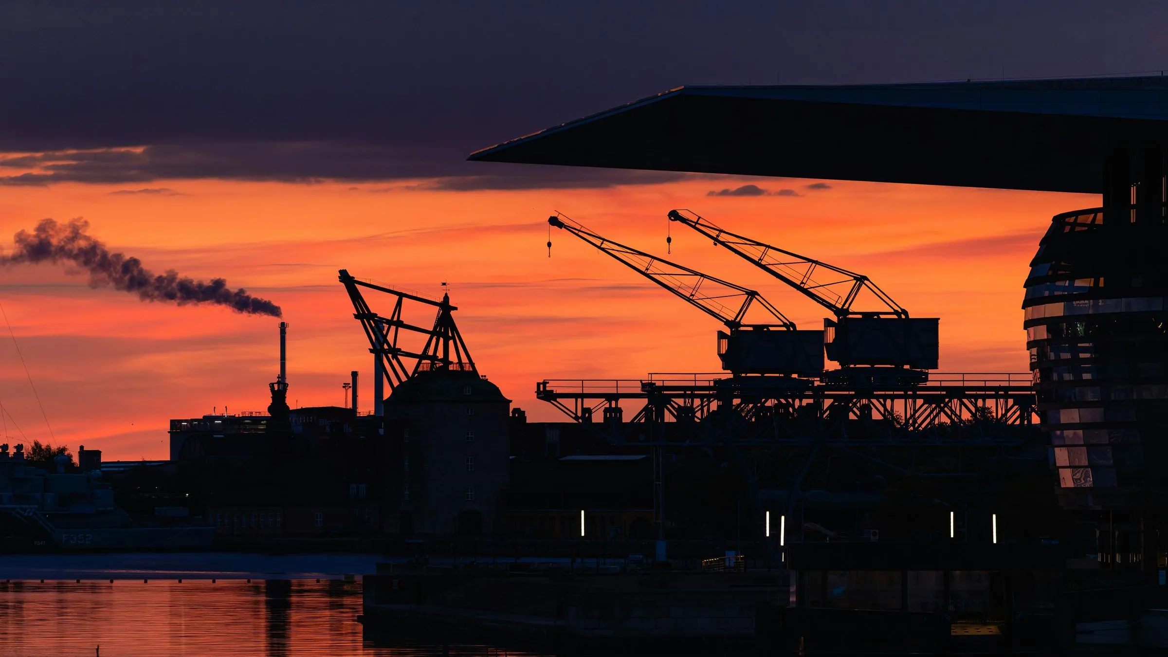 Port cranes silhouetted against an orange sunset